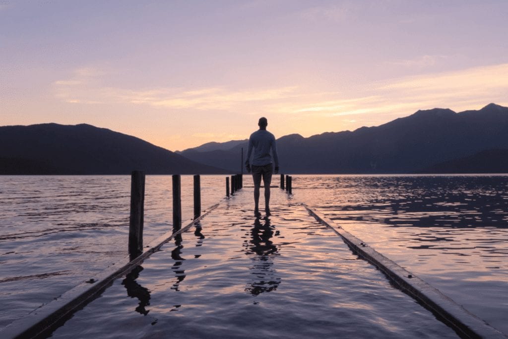 Man at the end of a dock looking out on horizon