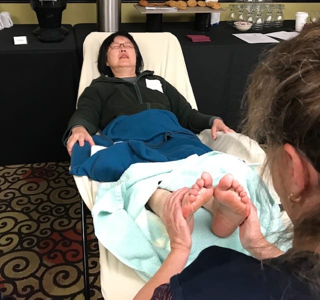 woman with green jacket gets a reflexology session