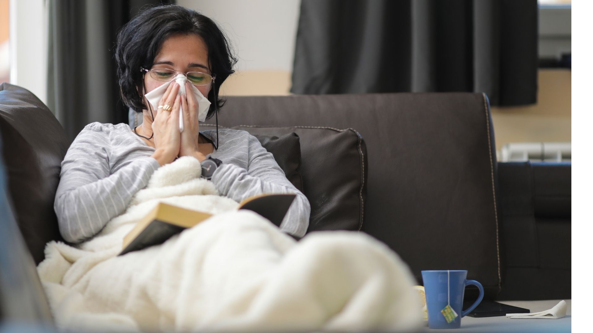 woman on sofa blowing out her nose